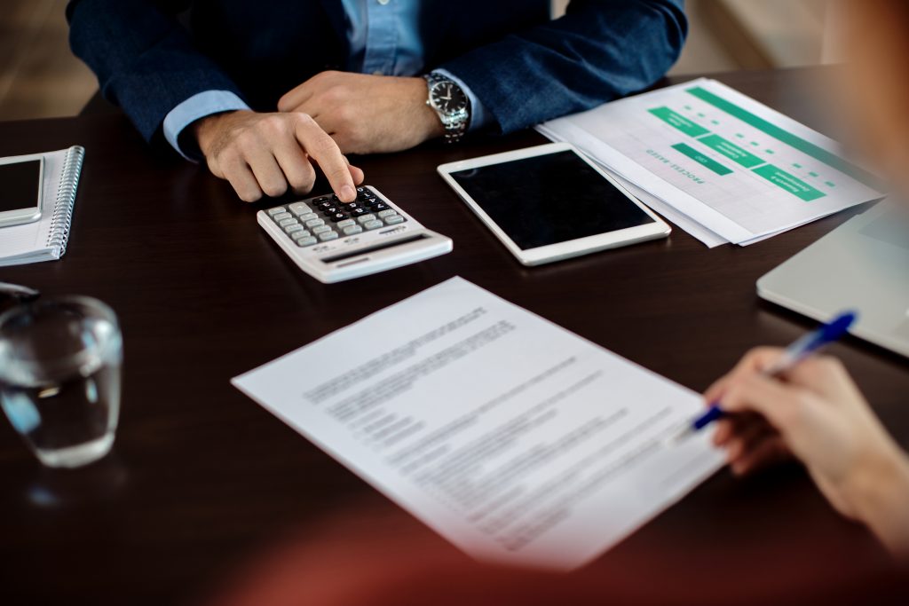 Closeup Real Estate Agent Using Calculator While His Client Is Signing Contract 1024x683