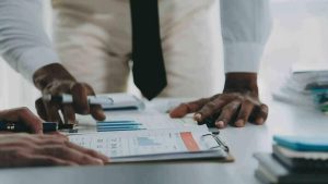 group of confident business people point to graphs and charts to analyze market data, balance sheet, account, net profit to plan new sales strategies to increase production capacity 