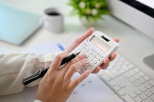a closeup image of a woman using a calculator at a table checking and calculating her budget premium photo